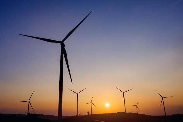 De turbine van de silhouetwind produceert van elektro met zonsonderganghemel