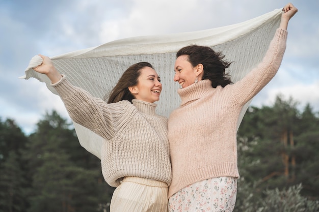 De twee gelukkigste vrouwen genieten van het leven en kijken in de verte meisjes in lichte truien met een grote knoop...