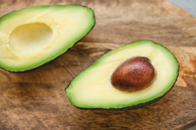 De twee helften van avocado op houten raad