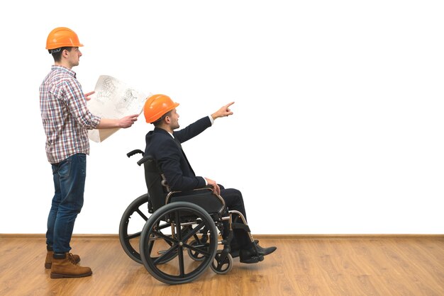 De twee ingenieurs met een rolstoelgebaar op de witte muurachtergrond