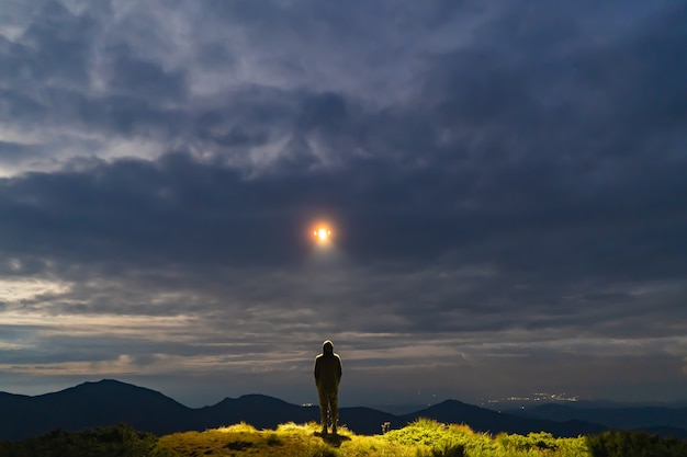 De UFO schijnt op een mannetje dat op de berg staat