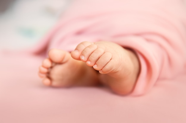 De uiterst kleine tenen van het babymeisje op roze oppervlakte in een selectief nadruk, moederschap en babyhoodeconcept
