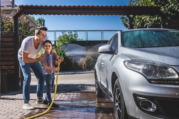 De vader en zoon die de auto wassen