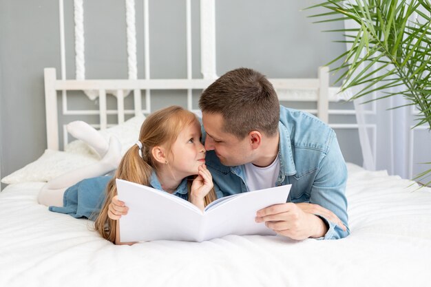 De vader leest een boek of studeert met het kind van de dochter voordat hij naar bed gaat of heeft plezier