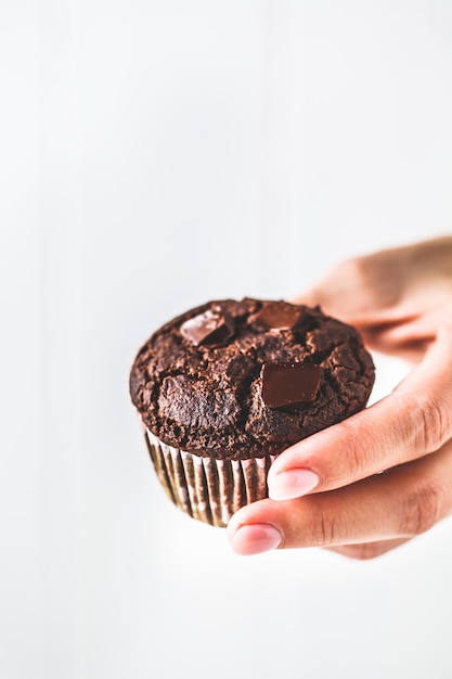 De veganistmuffin van de chocolade in een document kop op wit