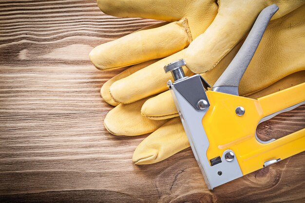 De veiligheidshandschoenen van het nietpistool op het concept van de houten raadsconstructie