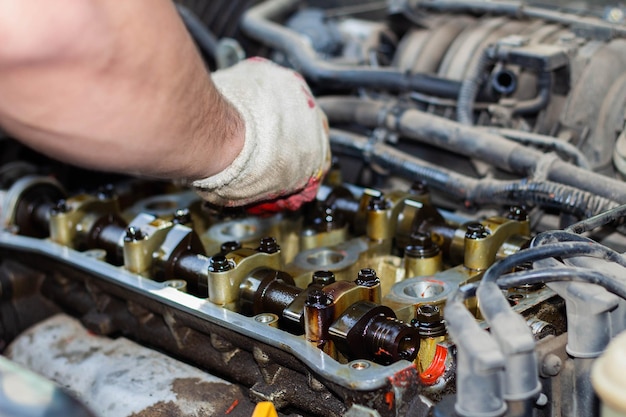 De verbrandingsmotor gedemonteerd de hand van de reparateur reinigt de cilinderkop