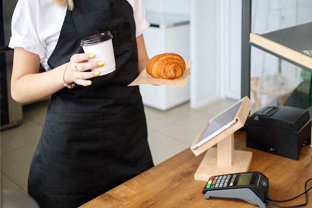 Foto de verkoper in het café verkoopt koffie en croissants