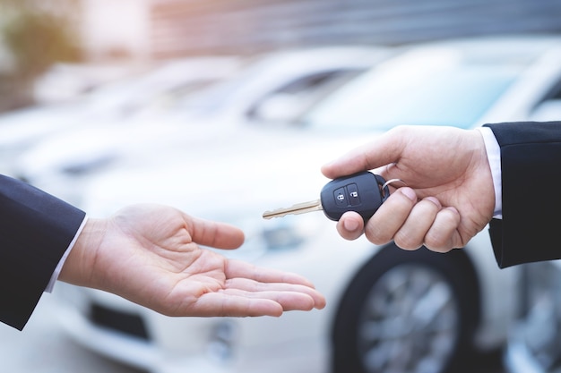 De verkoper levert de nieuwe autosleutels in de showroom aan de klant.