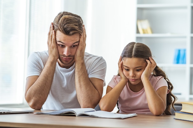 De vermoeide vader en een dochter die huiswerk maken aan de balie