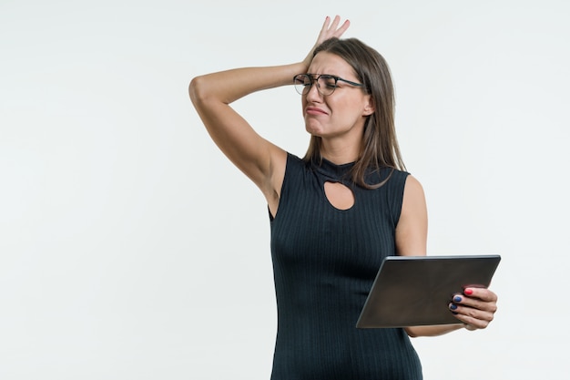 De verraste bedrijfsvrouw met een geschokt gezicht houdt een digitale tablet