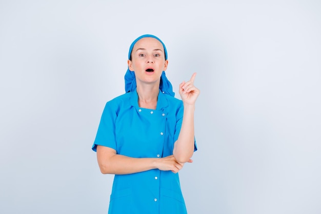 De verraste jonge verpleegster toont een miniem gebaar op witte achtergrond