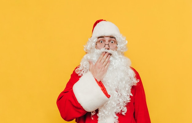 De verraste Kerstman raakt zijn mond met zijn hand aan die een verbaasd gebaar toont