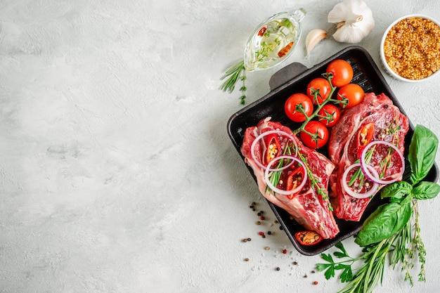 De verse lapjes vlees van het kalfsvlees op grillpan met kruiden en specerijen op concrete achtergrond