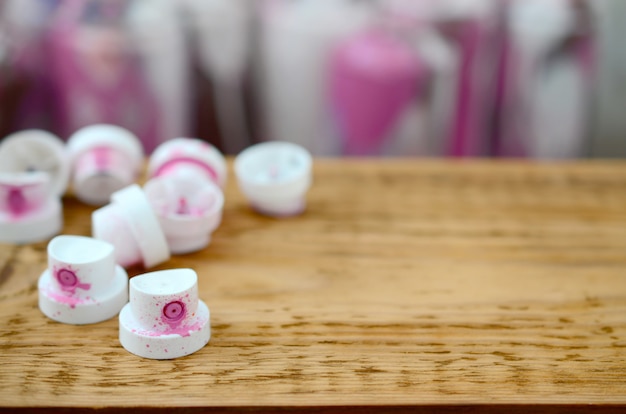 De vervuilde roze spuitmonden van de verfspuit liggen op een houten plank