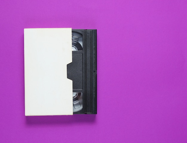 De videoband in een papieren doos op een paarse achtergrond
