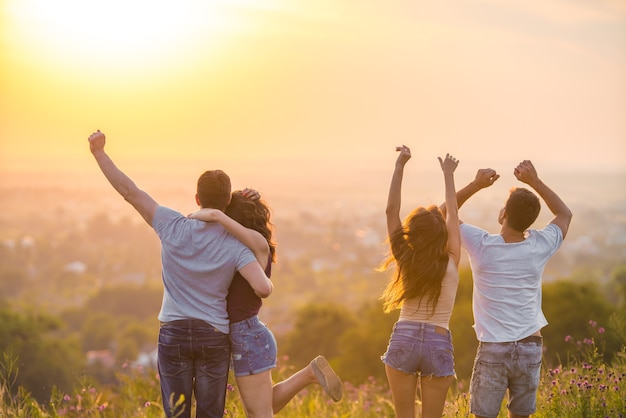 De vier actieve mensen dansen op de zonsondergang op de achtergrond