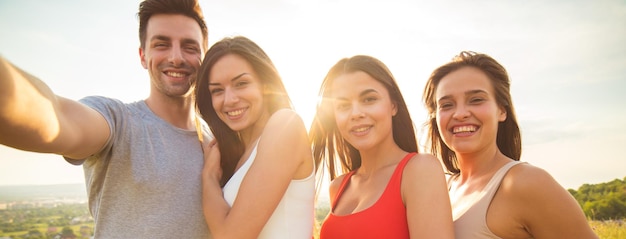 De vier gelukkige mensen maken een selfie op de felle zonachtergrond