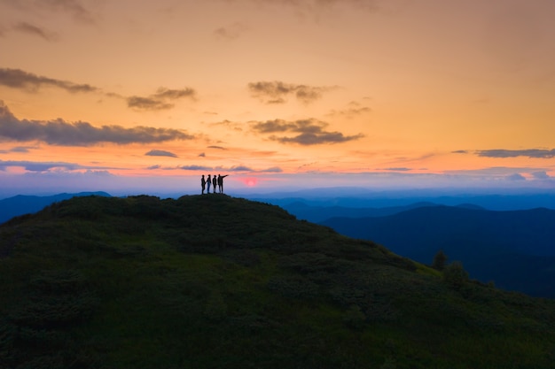 De vier mensen die op de pittoreske berg staan op de achtergrond van de zonsopgang