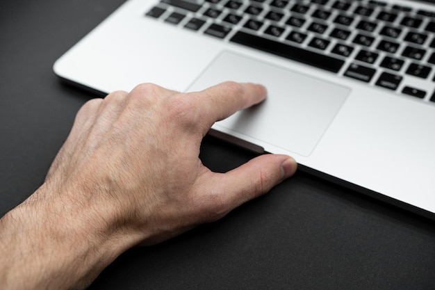 De vinger raakt het touchpad van de laptop Technologieconcept Geïsoleerd op zwarte achtergrond