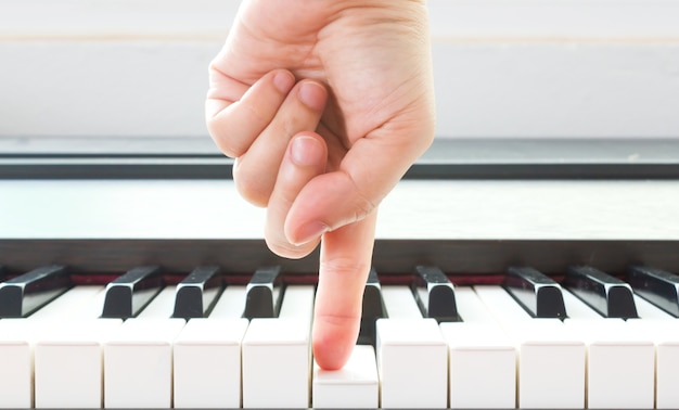 De vinger van de vrouw die op pianosleutel richt.