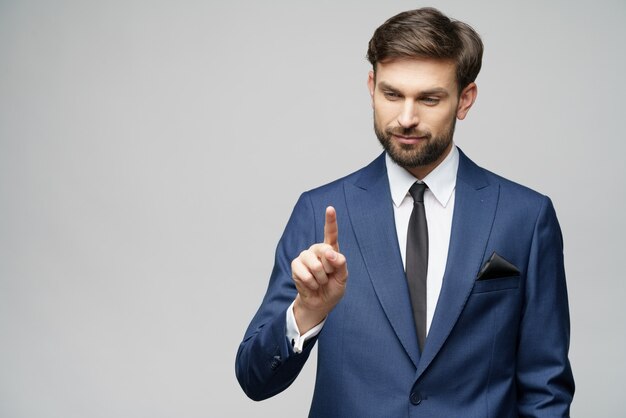 De vinger van het zakenmanpunt op het onzichtbare scherm, die digitale virtuele knoop over grijze muur drukken