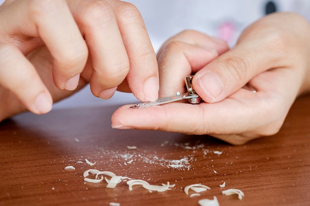 De vingernagels van de close-upvrouw worden nagelvijl. Het concept van zorg, schone vingernagels.