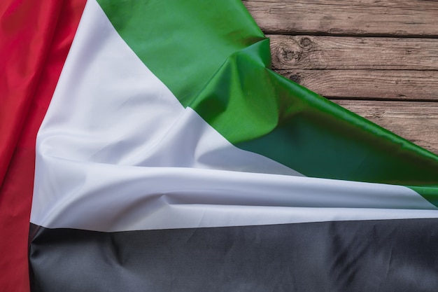 De vlag van de Verenigde Arabische Emiraten ligt op een bruine houten achtergrond met ruimte voor tekst of afbeelding