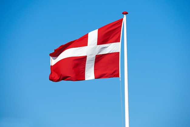 De vlag van Denemarken en de wind op de lucht achtergrond voor cultuur eer en protocol in het koninkrijk Symbool nationalisme en internationale identificatie in Scandinavië met royalty vertegenwoordiging en mockup ruimte