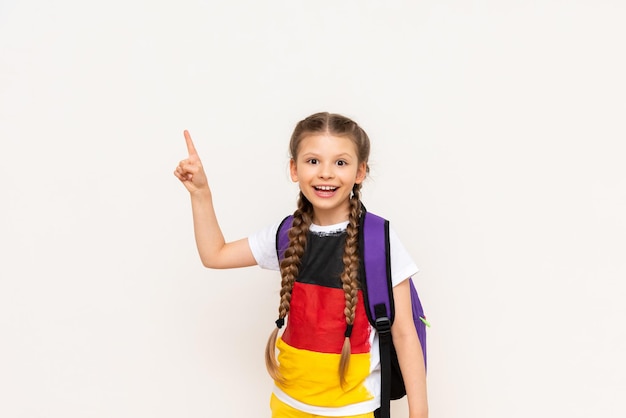 De vlag van Duitsland op de tshirt van een klein meisje Een mooi kind met staartjes wijst met zijn wijsvinger naar uw advertentie op een witte geïsoleerde achtergrond Taalcursussen voor kinderen