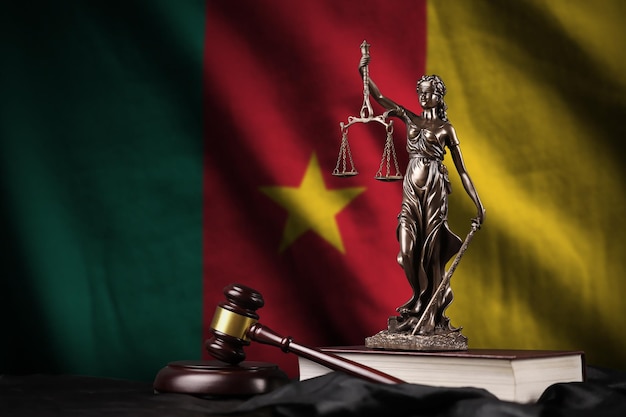 De vlag van Kameroen met standbeeld van de grondwet van Vrouwe Justitia en rechterhamer op zwarte draperie Concept oordeel en schuld