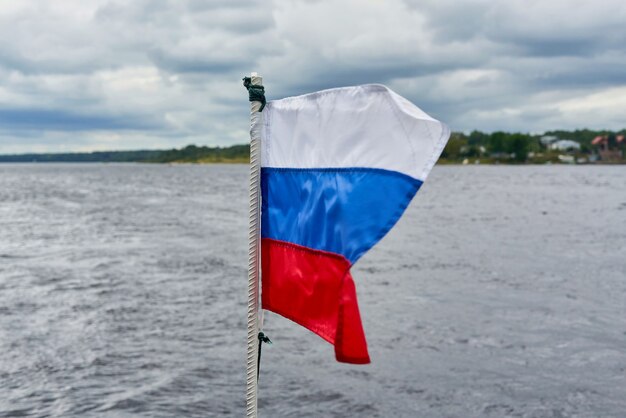 De vlag van Rusland vliegt in de wind tegen de achtergrond van het zeegezicht