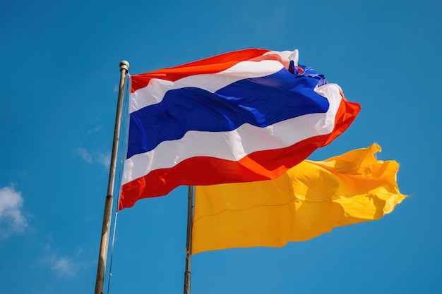 De vlag van Thailand en de gele dhammacakka-vlag op het Thaise tempelgebied wapperen in de wind