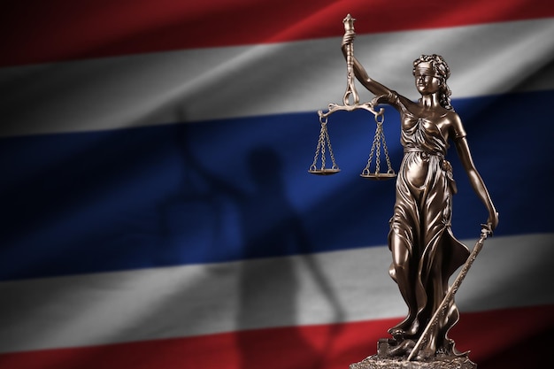 De vlag van Thailand met het standbeeld van Vrouwe Justitia en gerechtelijke schalen in het donkere kamerconcept oordeel en