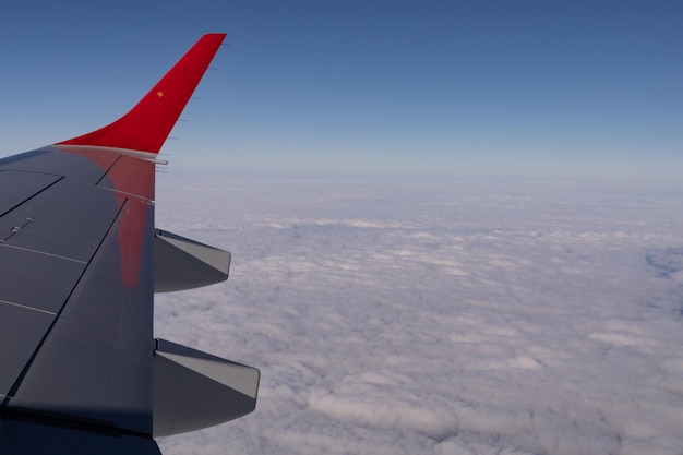 De vleugel van een vliegend vliegtuig tegen de achtergrond van wolken