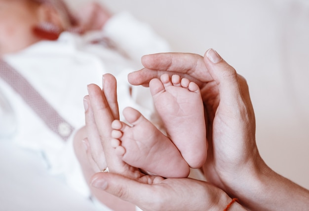 De voeten van de pasgeboren baby op vrouwelijke handenclose-up.