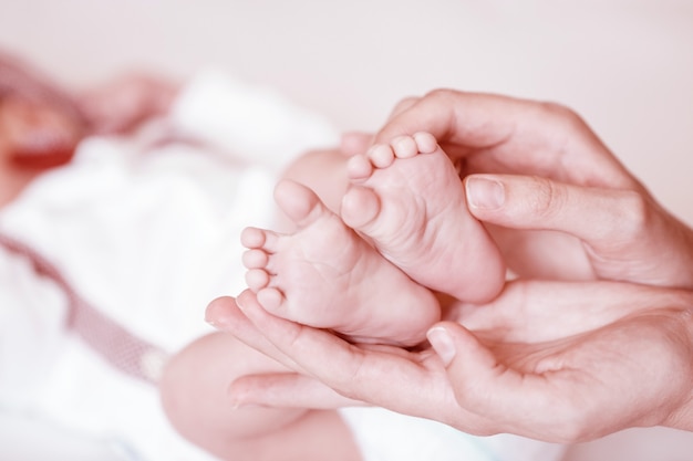 De voeten van de pasgeboren baby op vrouwelijke handenclose-up.