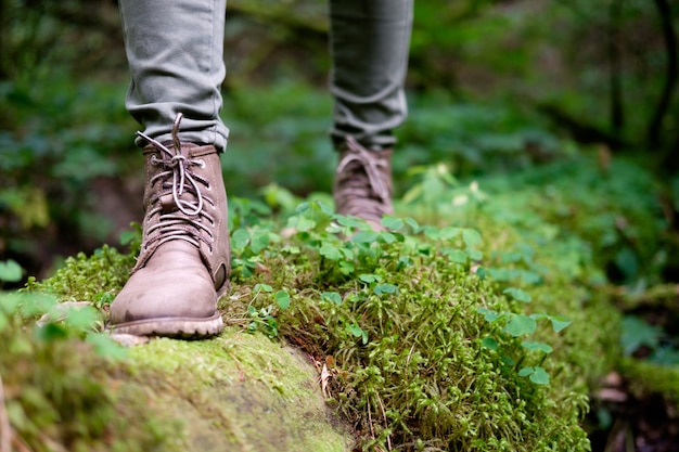 De voeten van de vrouw in reislaarzen bemoste login het bos. Reizen concept.