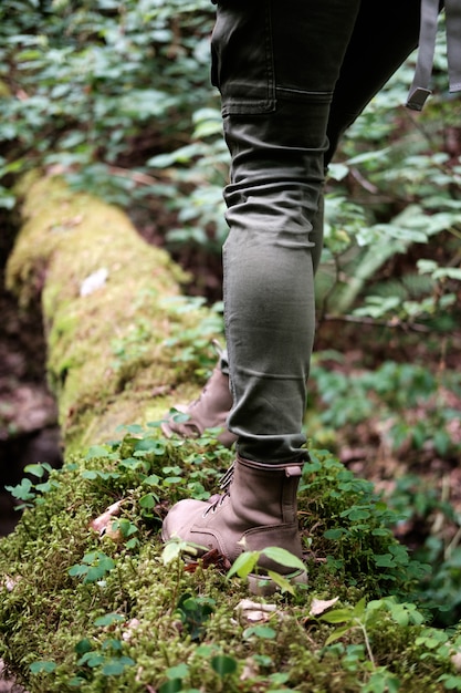 De voeten van de vrouw in reislaarzen op bemoste login het bos. Reizen concept.