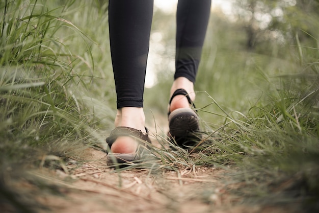 De voeten van de vrouw op de met gras begroeide landweg