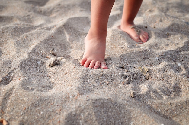 De voeten van kleine kinderen op het zandstrand in de zomer.