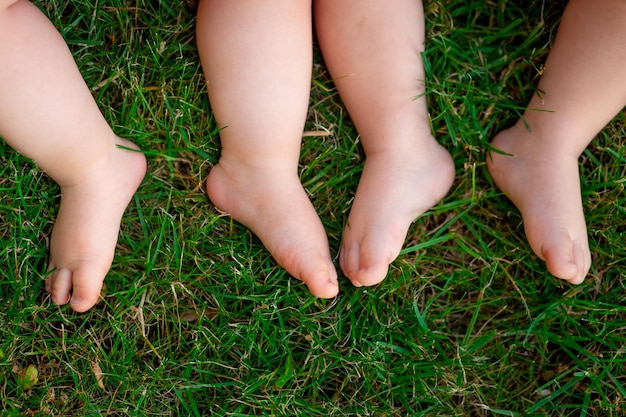 De voeten van twee baby's op de groene grasruimte voor tekst