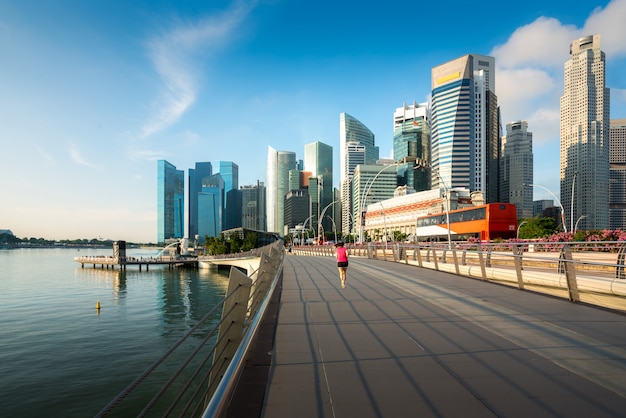 De voetgangers lopen langs brug dichtbij Jachthavenbaai in Singapore met de wolkenkrabber van Singapore op achtergrond