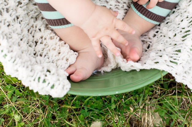 De voetjes van een baby worden getoond in een groene kom op het gras.