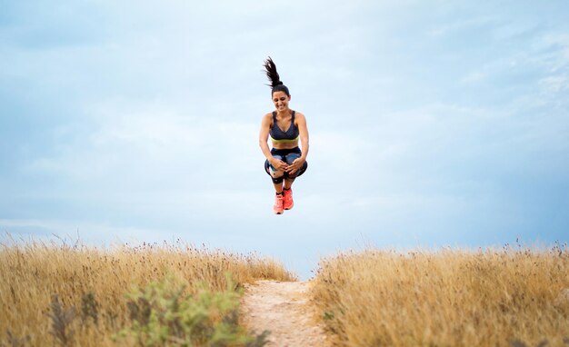Foto de volledige lengte van een jonge vrouw die op grasland springt