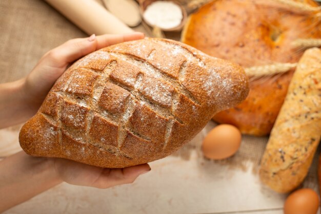 De voorbereiding van brood, vers brood in handenclose-up op oude houten achtergrond, concept om te bakken