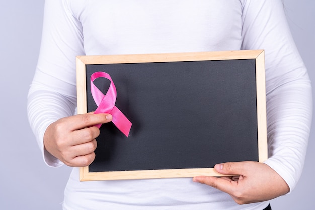 De voorlichtingslint van borstkanker op bordgreep door vrouw