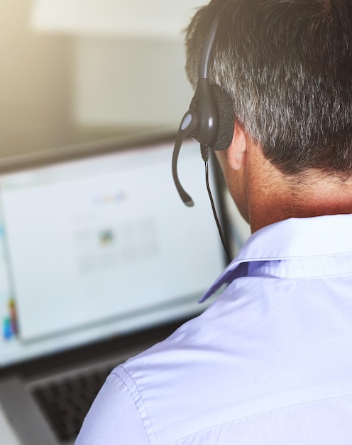 De vraag loggen Over de schouder geschoten van een man die op zijn laptop werkt