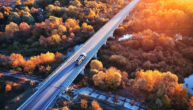 De vrachtwagen rijdt over de brug over de rivier Drone uitzicht op het herfstbos