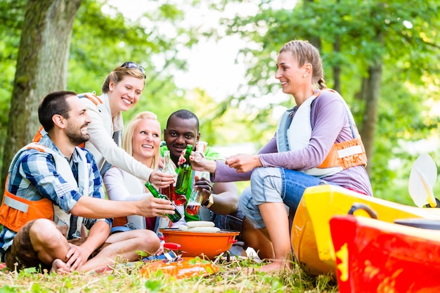 De vrienden barbecueën na sporten in bos het drinken bier